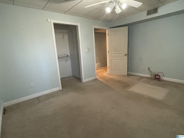 unfurnished bedroom with carpet flooring, a paneled ceiling, ceiling fan, and a closet