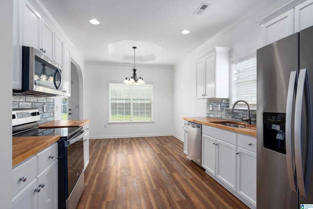 kitchen with sink, butcher block countertops, white cabinetry, appliances with stainless steel finishes, and pendant lighting