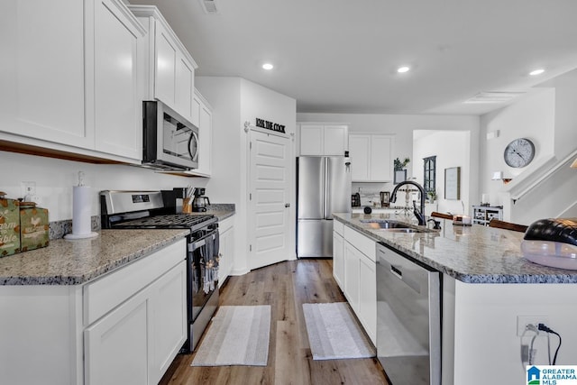 kitchen featuring stainless steel appliances, sink, a center island with sink, and white cabinets