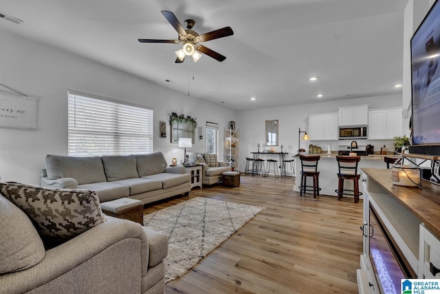 living room featuring ceiling fan, plenty of natural light, and light wood-type flooring