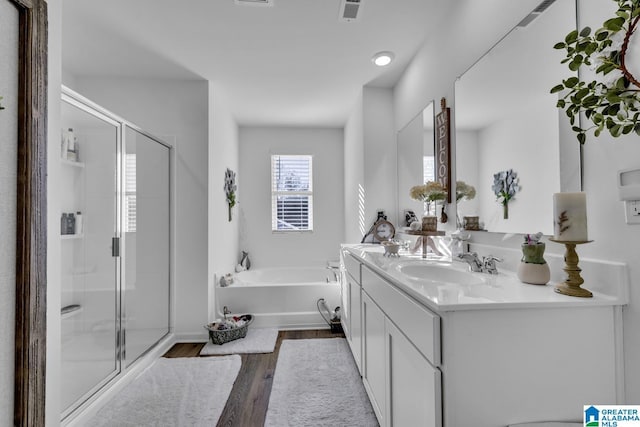 bathroom with hardwood / wood-style flooring, plus walk in shower, and vanity