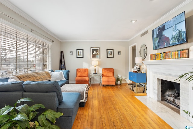 living room with a premium fireplace, wood-type flooring, and crown molding