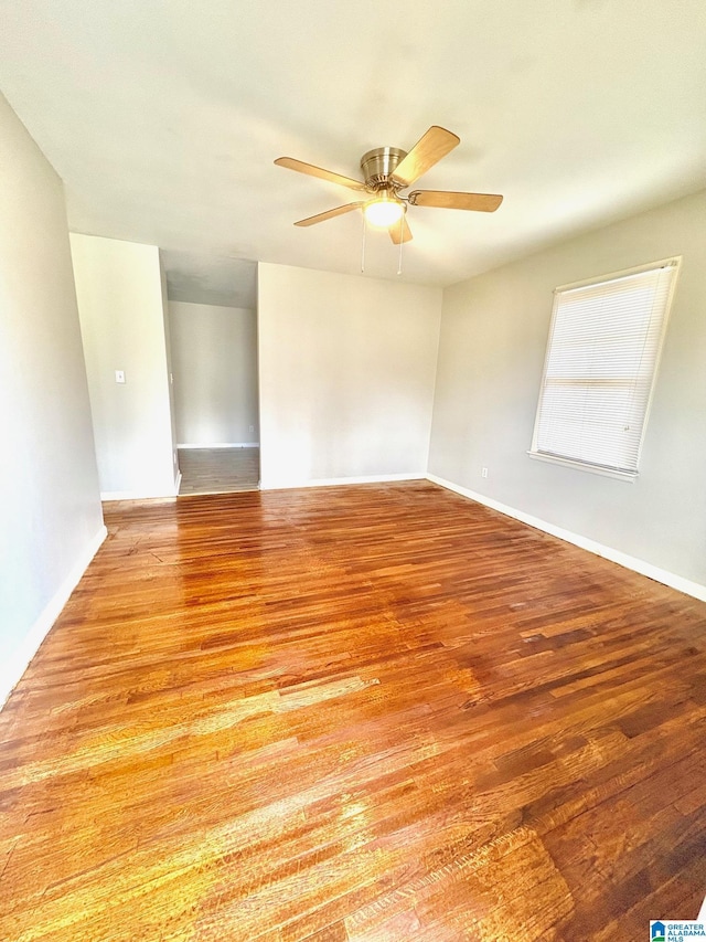 unfurnished room with a ceiling fan, baseboards, and light wood-type flooring