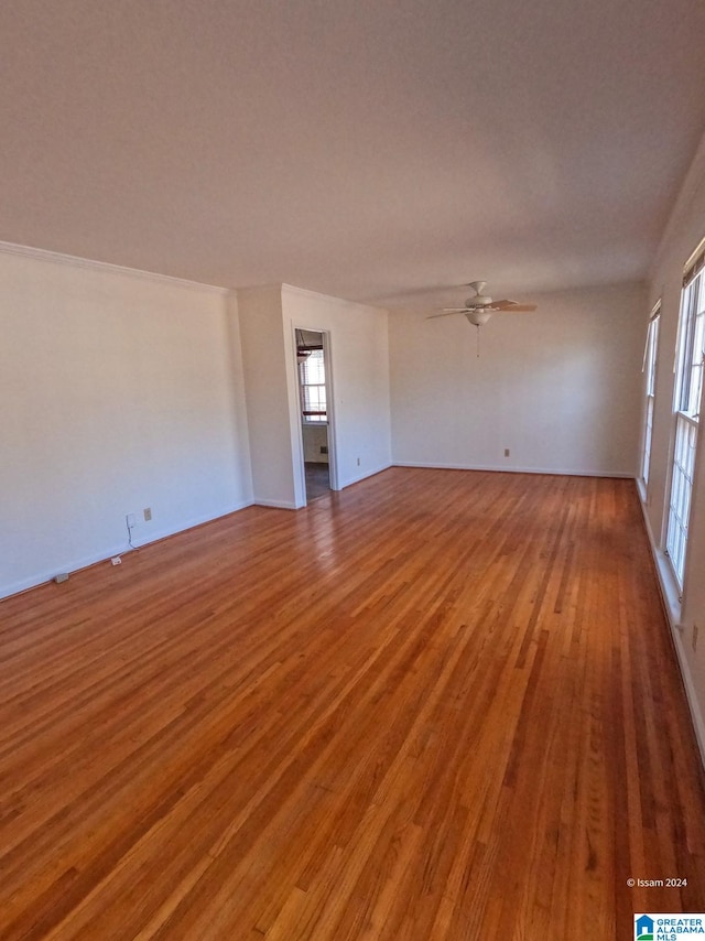 empty room with ceiling fan, wood-type flooring, and a wealth of natural light