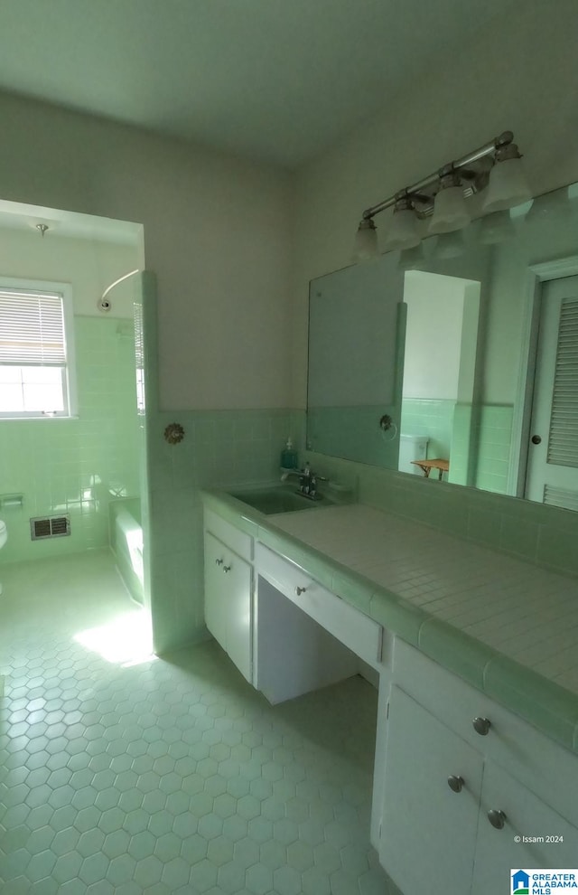 bathroom featuring tile patterned flooring, vanity, a shower, and tile walls