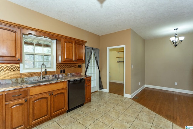 kitchen featuring sink, light tile patterned floors, dishwasher, decorative backsplash, and dark stone counters