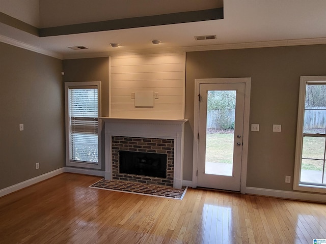 unfurnished living room featuring plenty of natural light, a brick fireplace, and light wood-type flooring