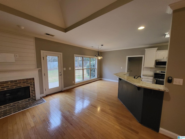 kitchen featuring appliances with stainless steel finishes, white cabinets, hanging light fixtures, light stone countertops, and light wood-type flooring