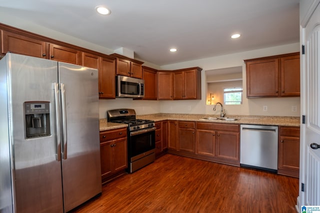 kitchen featuring light stone counters, stainless steel appliances, dark hardwood / wood-style floors, and sink