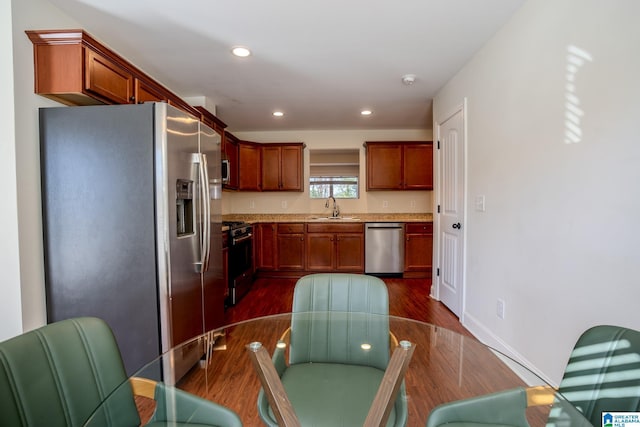 kitchen with light stone counters, sink, dark wood-type flooring, and appliances with stainless steel finishes