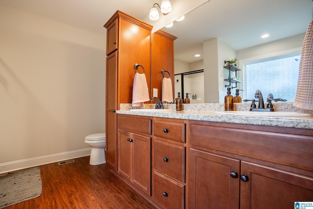 bathroom with a shower with door, vanity, hardwood / wood-style floors, and toilet