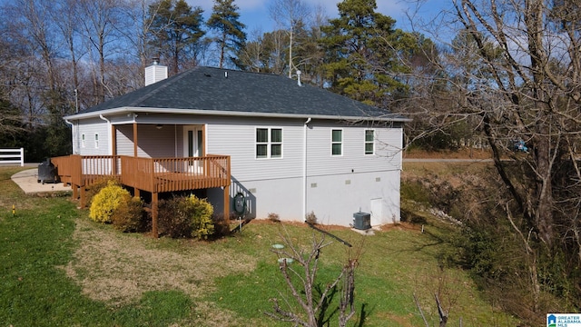 rear view of property featuring central AC unit, a yard, and a deck