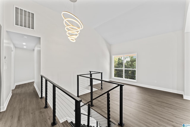 hall with dark hardwood / wood-style flooring, vaulted ceiling, and a notable chandelier