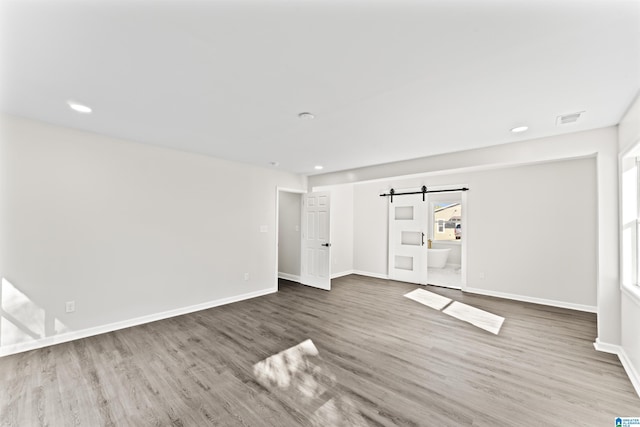 spare room featuring wood-type flooring and a barn door