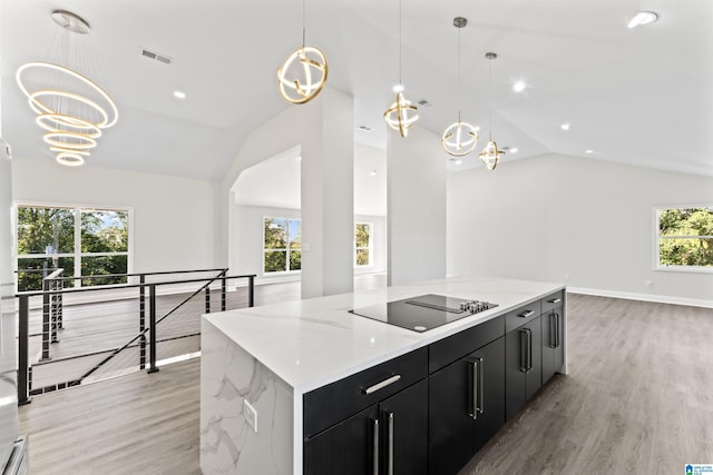 kitchen with a spacious island, light hardwood / wood-style flooring, black electric cooktop, a notable chandelier, and pendant lighting