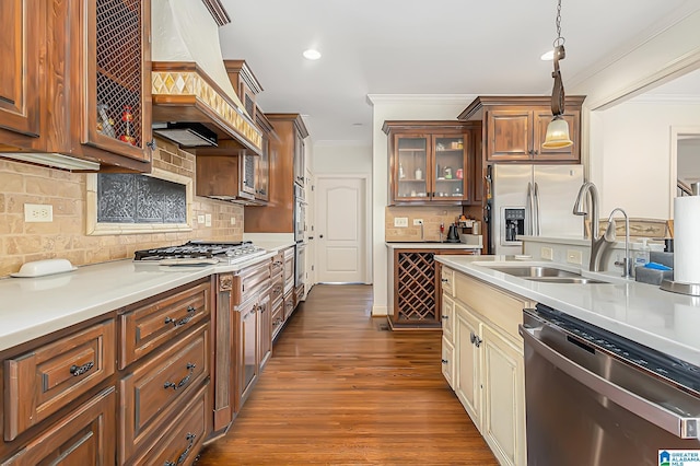 kitchen with sink, decorative light fixtures, custom range hood, stainless steel appliances, and decorative backsplash