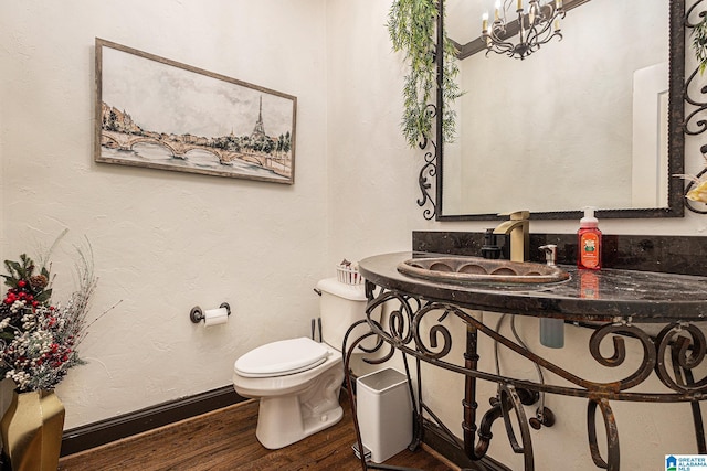 bathroom featuring hardwood / wood-style flooring, toilet, sink, and a notable chandelier