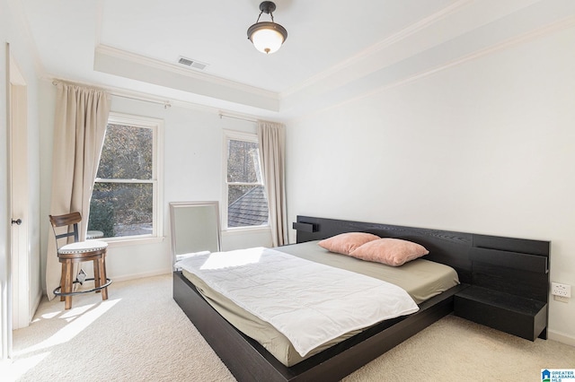 bedroom featuring ornamental molding, light carpet, and a tray ceiling