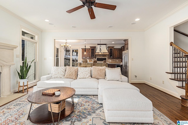 living room with ornamental molding, dark hardwood / wood-style flooring, and ceiling fan with notable chandelier