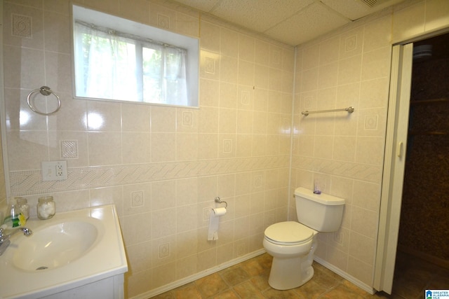 bathroom with tile walls, vanity, tile patterned floors, and toilet