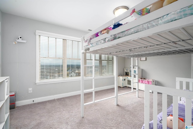 bedroom with multiple windows, carpet floors, and refrigerator