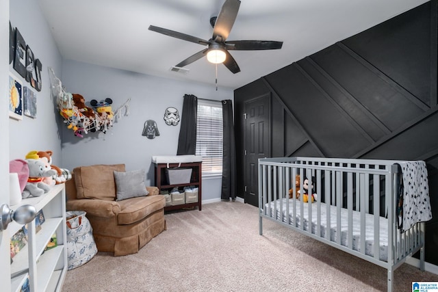 bedroom with ceiling fan, carpet floors, and a crib