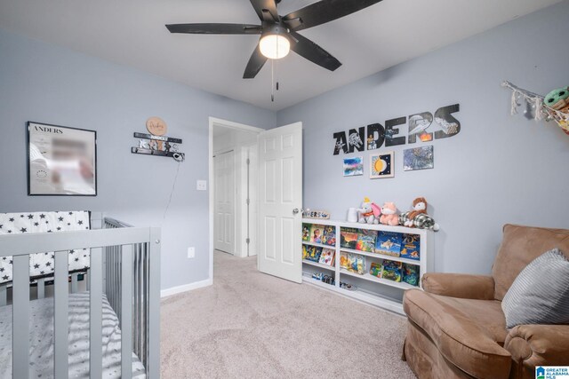 bedroom with a nursery area, light carpet, and ceiling fan