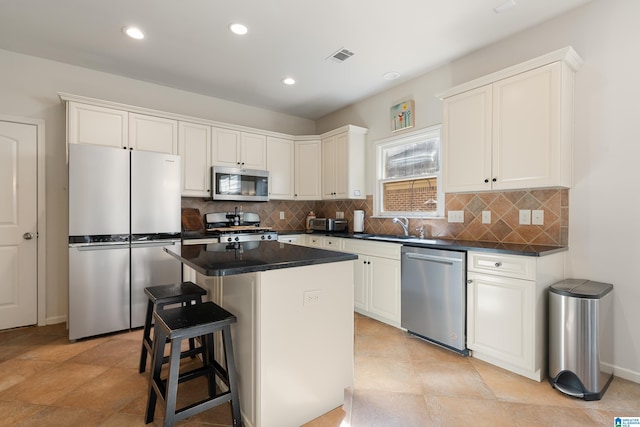 kitchen featuring a kitchen bar, sink, a kitchen island, stainless steel appliances, and white cabinets