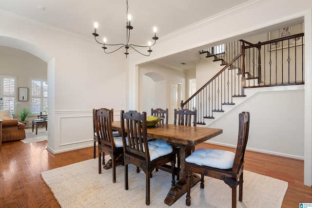 dining room with wood-type flooring, an inviting chandelier, and crown molding