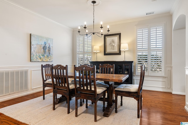 dining area featuring ornamental molding, wood-type flooring, and an inviting chandelier