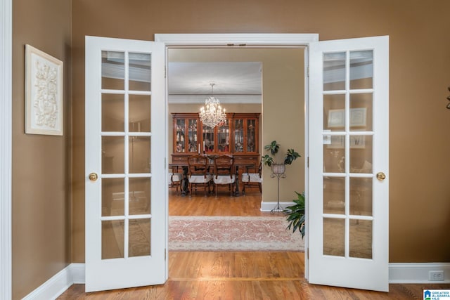 doorway to outside with french doors, ornamental molding, wood-type flooring, and a chandelier