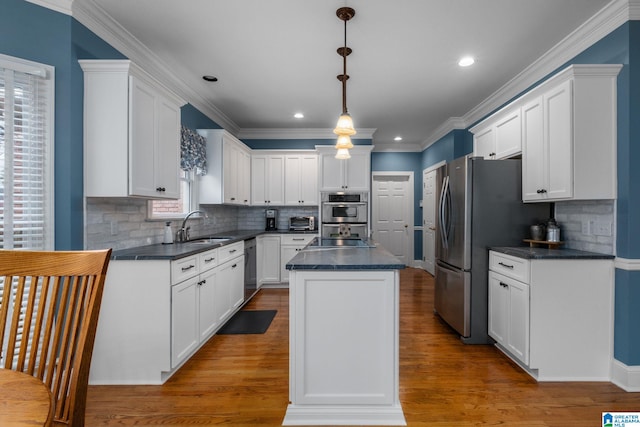 kitchen featuring a kitchen island, white cabinets, pendant lighting, stainless steel appliances, and backsplash