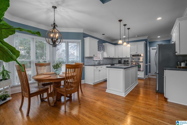 kitchen featuring hanging light fixtures, backsplash, sink, and white cabinets