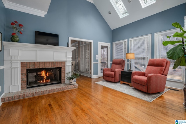 living room featuring a healthy amount of sunlight, a skylight, light hardwood / wood-style floors, and a brick fireplace