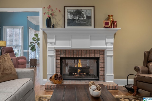 living room with a brick fireplace, wood-type flooring, and ornamental molding