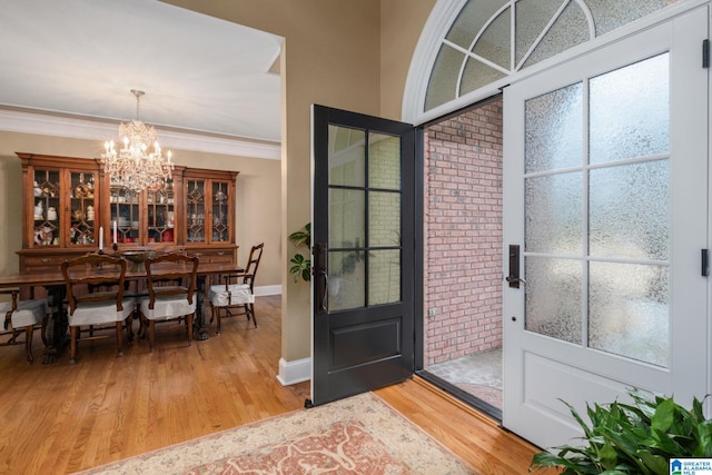 entryway with hardwood / wood-style flooring, ornamental molding, and a chandelier