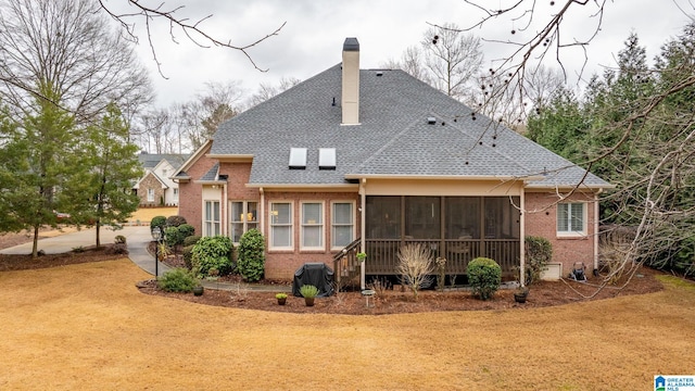 rear view of house featuring a lawn and a sunroom