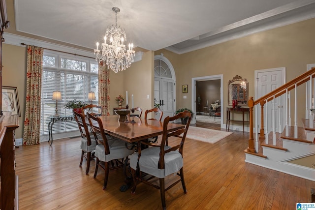 dining area with a chandelier, a raised ceiling, and light hardwood / wood-style flooring