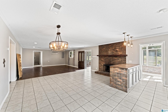 unfurnished living room with an inviting chandelier, light tile patterned floors, crown molding, and a fireplace