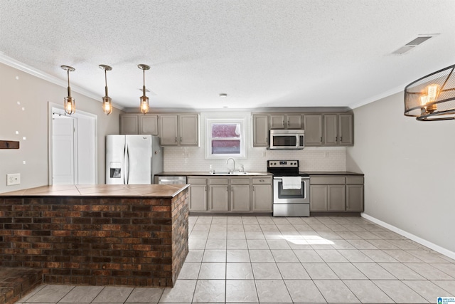 kitchen with sink, backsplash, hanging light fixtures, ornamental molding, and stainless steel appliances