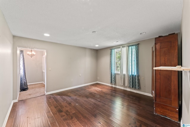 empty room with dark hardwood / wood-style flooring, a textured ceiling, and an inviting chandelier