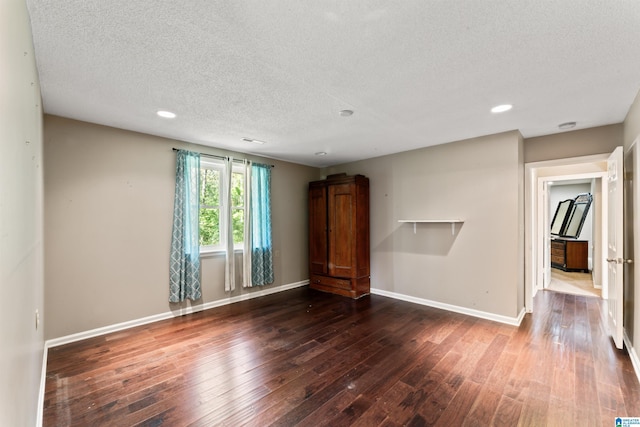 unfurnished room featuring dark wood-type flooring and a textured ceiling