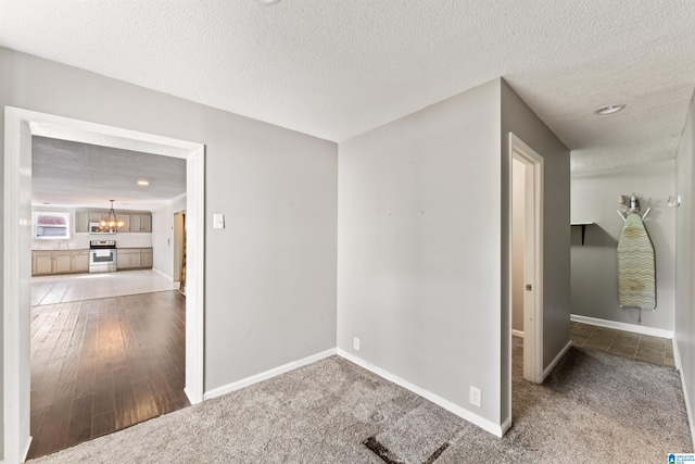 unfurnished room featuring an inviting chandelier, carpet flooring, and a textured ceiling