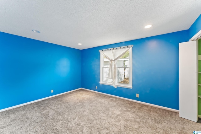 carpeted empty room with a textured ceiling