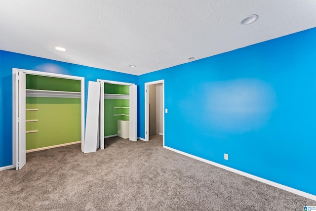 unfurnished bedroom featuring multiple closets and carpet flooring