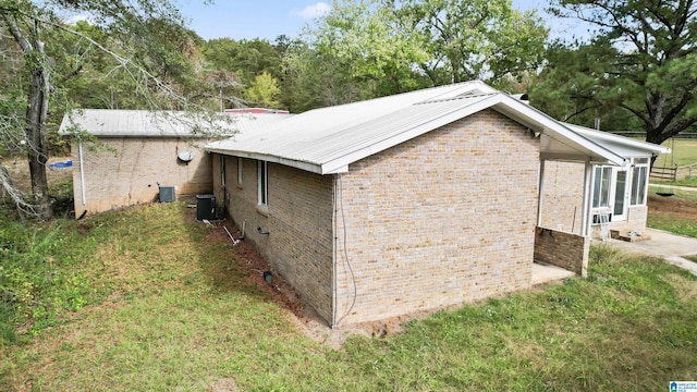 view of side of home with a yard and central air condition unit