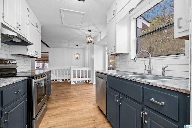 kitchen featuring sink, white cabinetry, stainless steel appliances, decorative backsplash, and decorative light fixtures