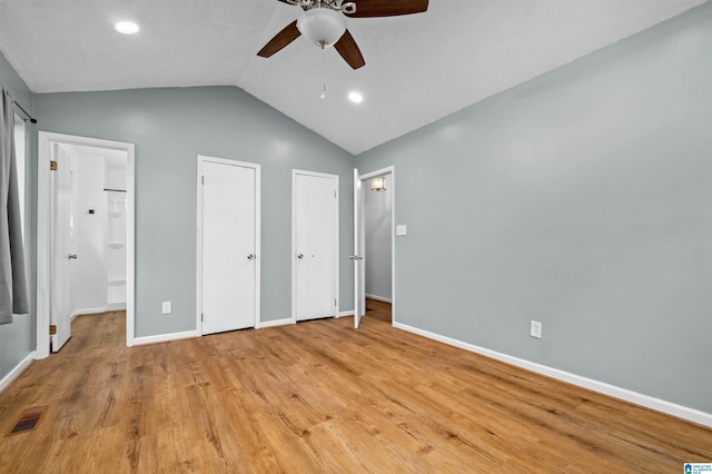 unfurnished bedroom featuring vaulted ceiling, ceiling fan, light hardwood / wood-style floors, and two closets