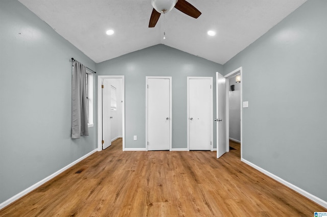 unfurnished bedroom with multiple closets, vaulted ceiling, light hardwood / wood-style floors, and ceiling fan