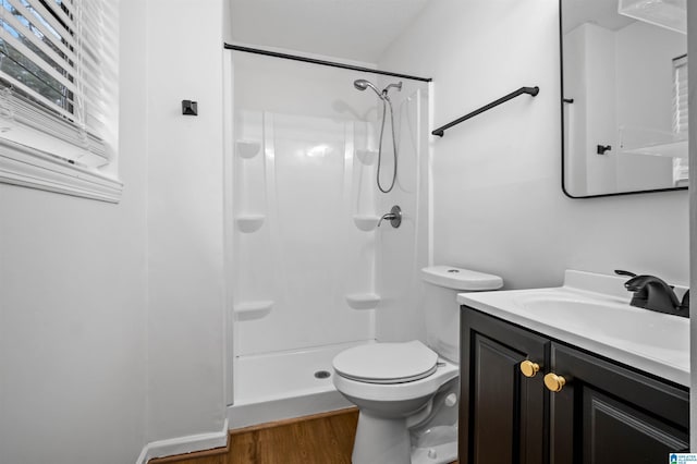 bathroom featuring hardwood / wood-style flooring, a shower, vanity, and toilet